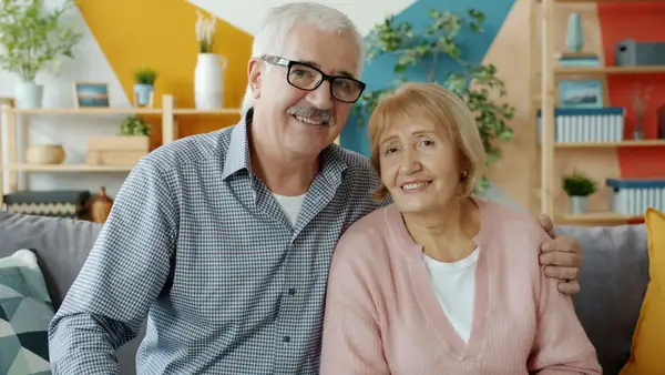 Couple de retraités souriants dans leur salon